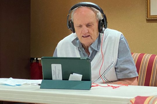 Senior man wearing headphones on a Zoom meeting