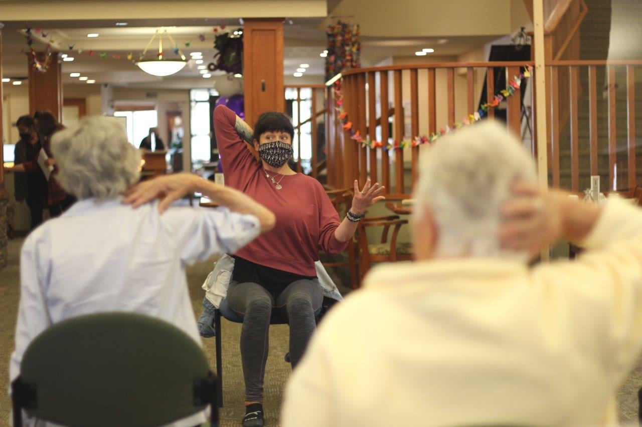 Fitness instructor in a mask leading a class with two senior women