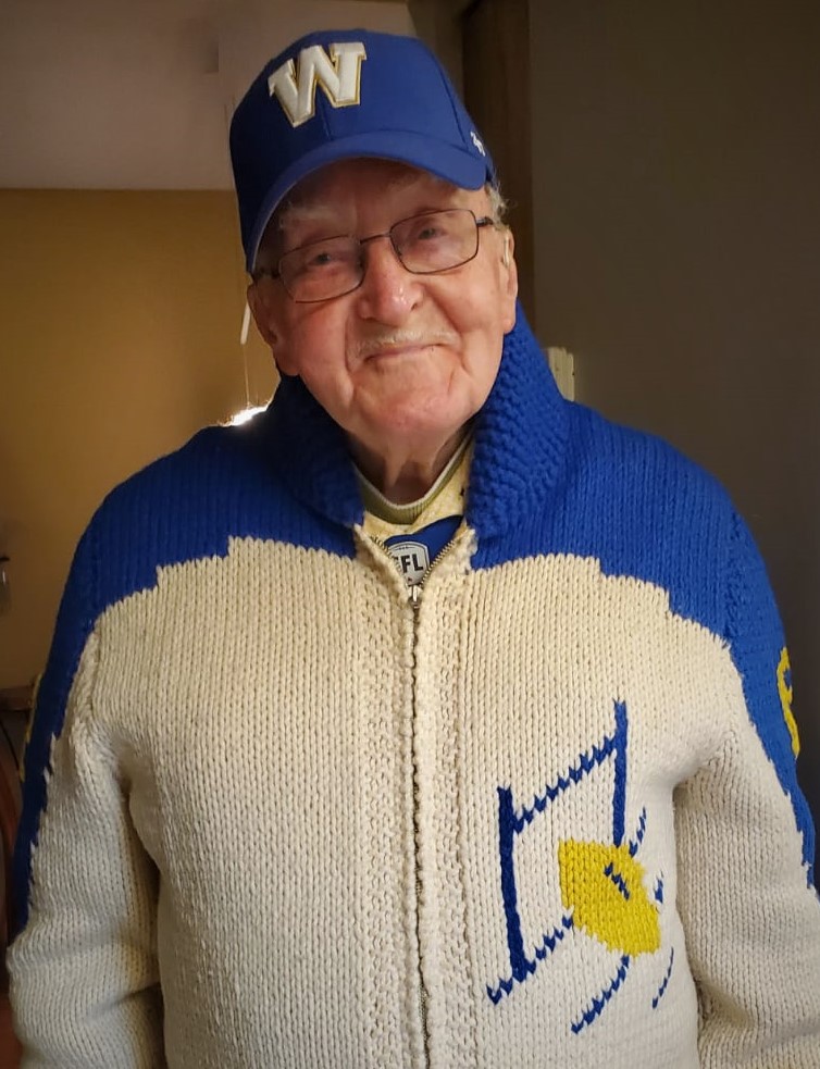 Smiling senior man over 100 years old in Winnipeg Blue Bombers sweater.