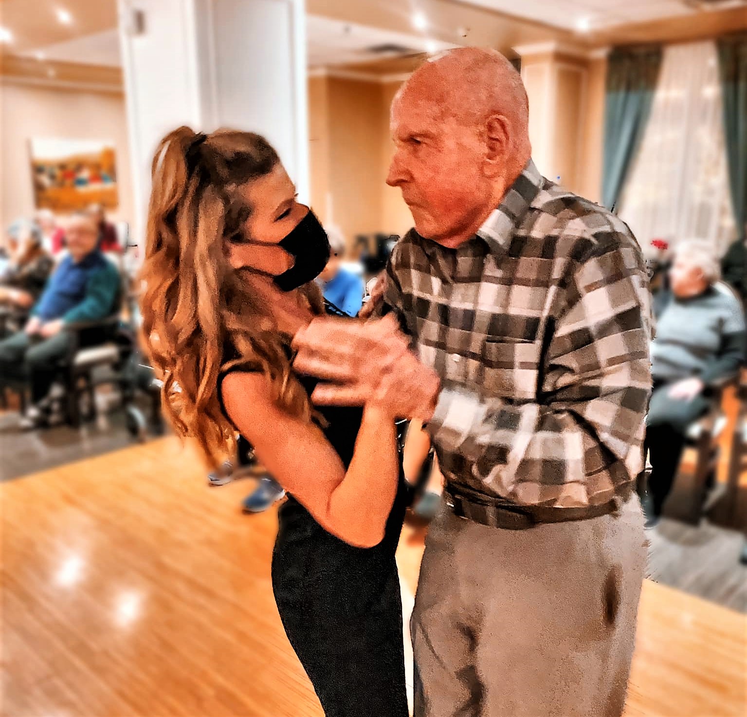 Young woman in little black dress dancing with senior man.