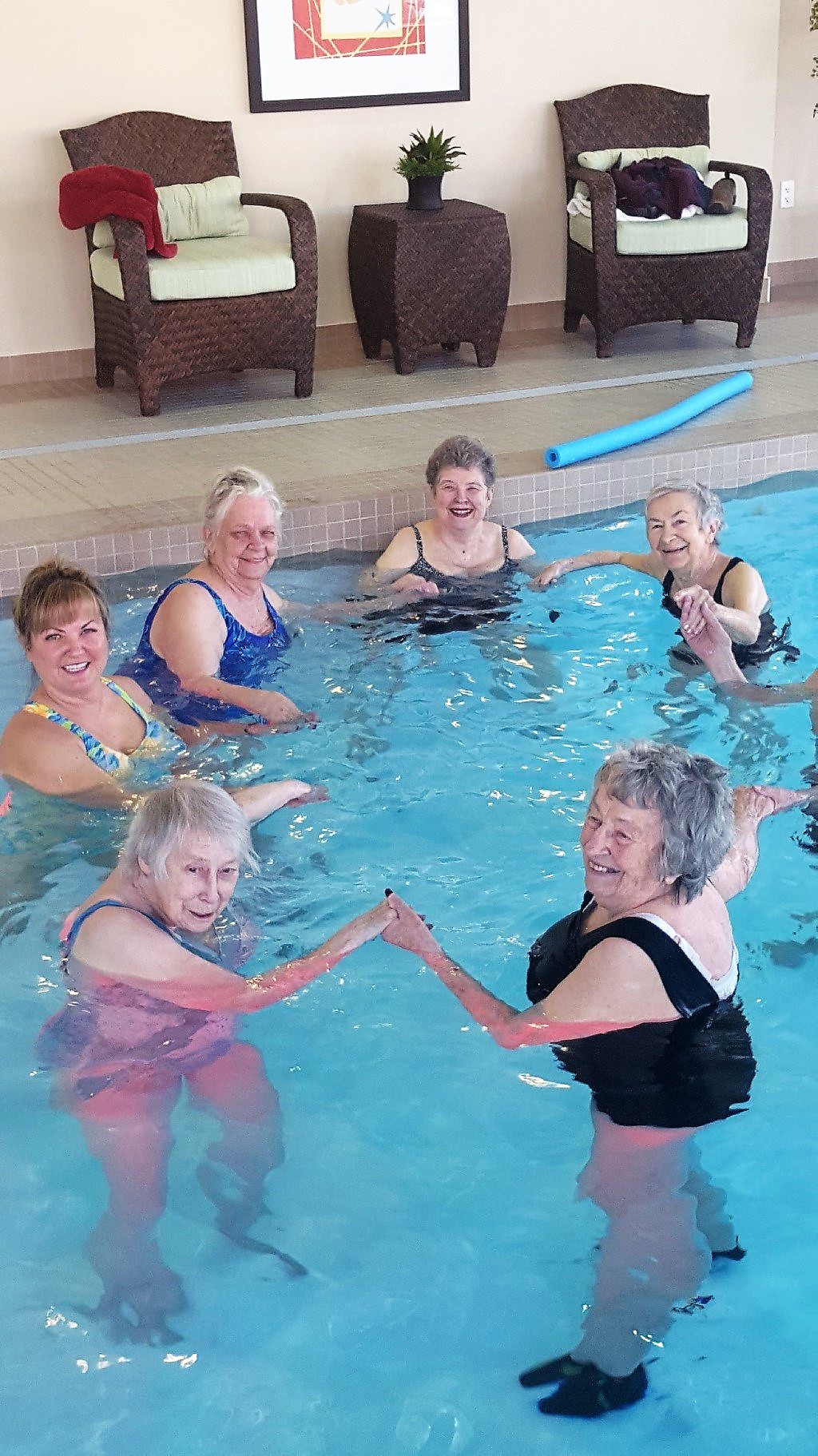 6 senior women standing in a circle and holding hands in a swimming pool