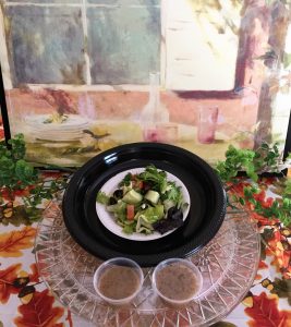 Greek salad with dressing on the side displayed in front of a frescoe